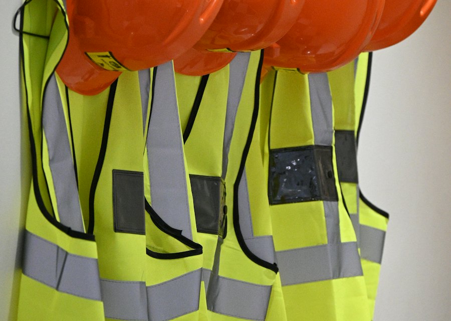 Capacetes e coletes de segurança pendurados, prontos para uso