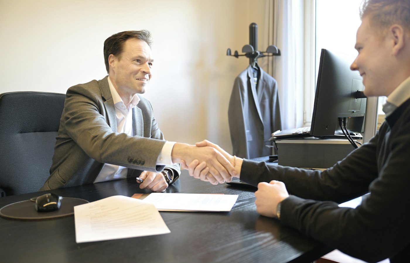 Empresário e consultor apertando as mãos sobre documentos da empresa