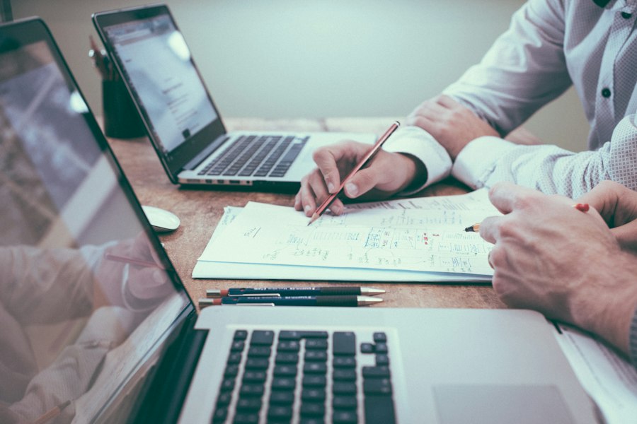 Profissionais analisando relatórios em uma mesa com notebooks