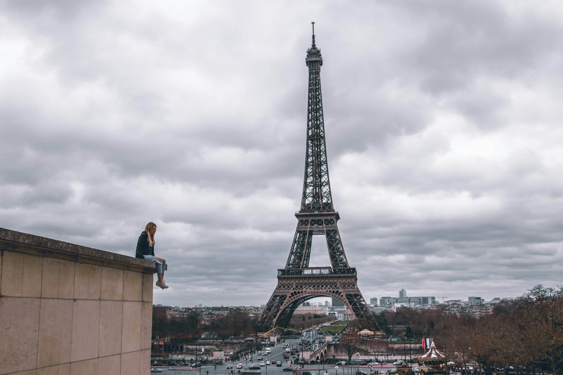 Pessoa sozinha diante da Torre Eiffel em um dia nublado